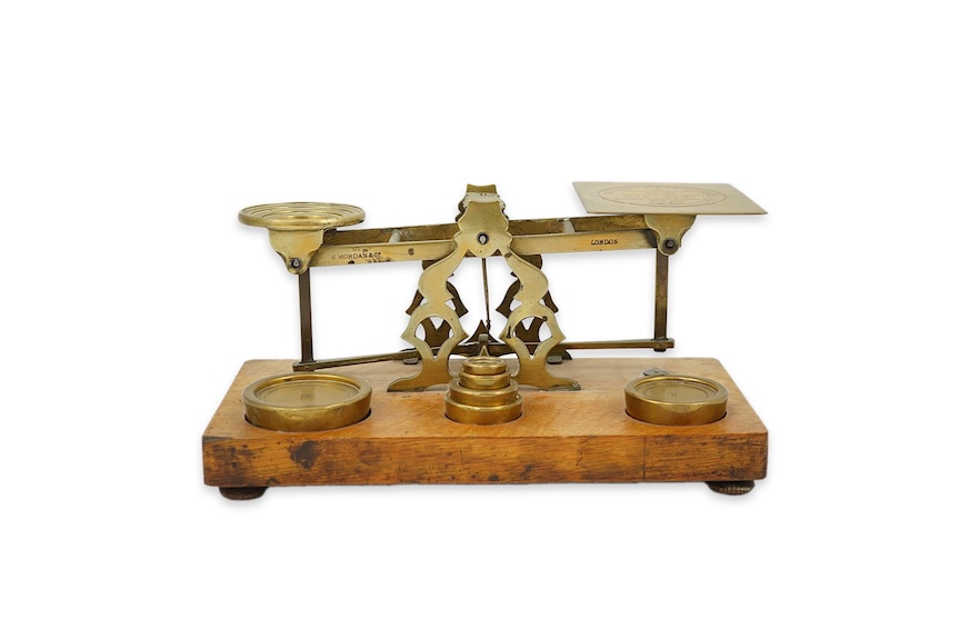 A Sampson Mordan & Co. set of brass postal scales on an oak base with weights, 27cm wide, with engraved prices for Inland Letter Post, etc.